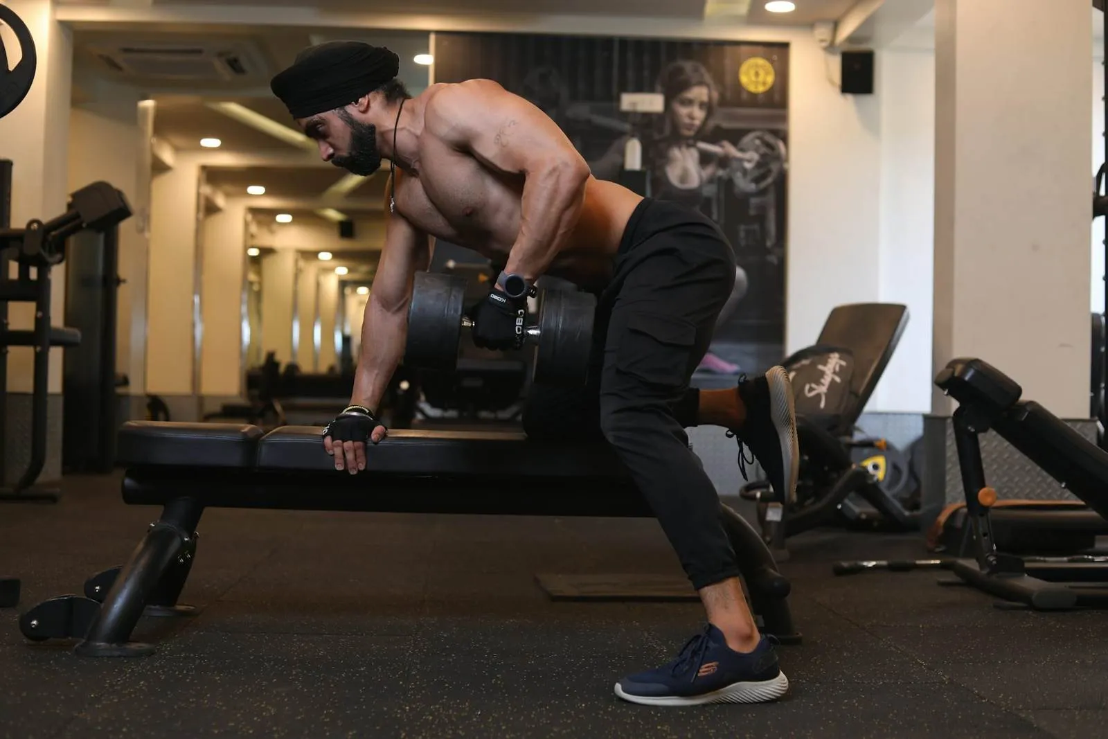 Member doing a dumbbell row on a bench in the gym